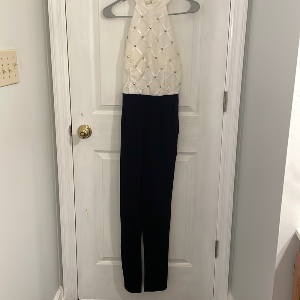 Women jumpsuit, white studded high neck halter top, black straight leg pant.